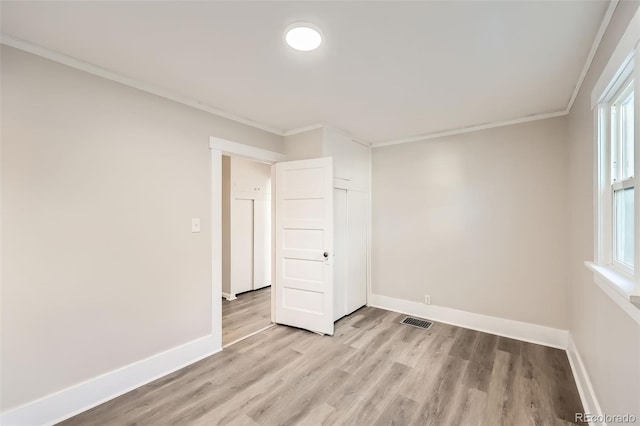 spare room with a healthy amount of sunlight, light wood-type flooring, and ornamental molding