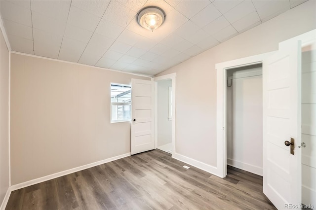 unfurnished bedroom featuring hardwood / wood-style flooring, lofted ceiling, and a closet