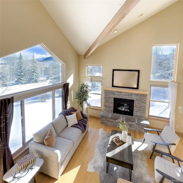 living room with lofted ceiling with beams, light hardwood / wood-style flooring, and a stone fireplace