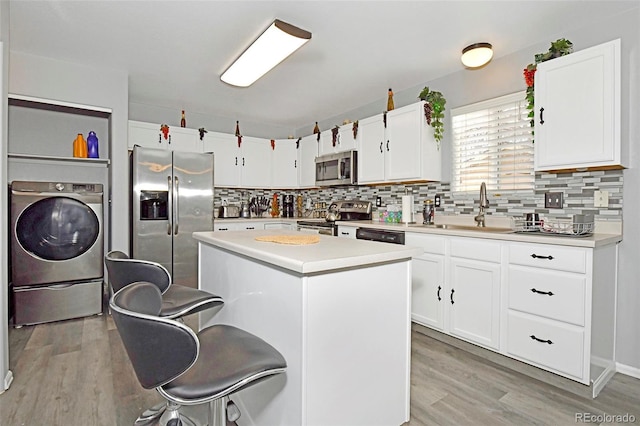 kitchen featuring light wood-type flooring, appliances with stainless steel finishes, washer / clothes dryer, and a sink