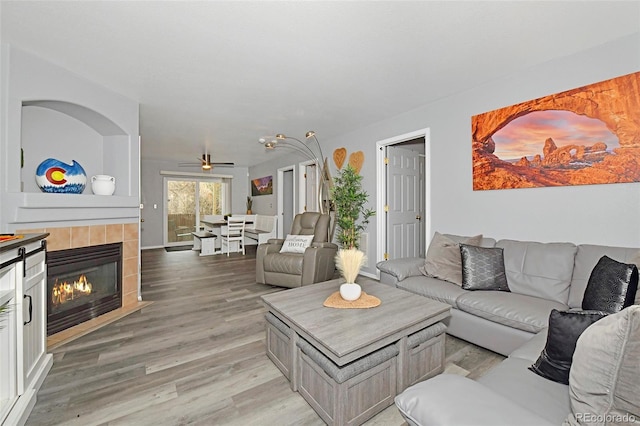 living area with light wood-type flooring and a tiled fireplace