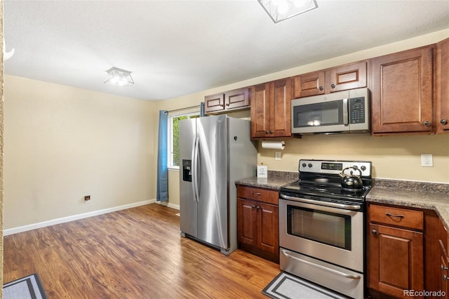 1209 Maxwell St, Colorado Springs, CO 80906 - kitchen featuring stainless steel appliances, dark countertops, light wood-type flooring, and brown cabinets