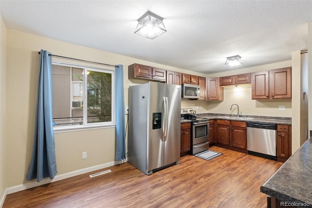 1209 Maxwell St, Colorado Springs, CO 80906 - kitchen with stainless steel appliances, dark countertops, light wood-style floors, and brown cabinetry
