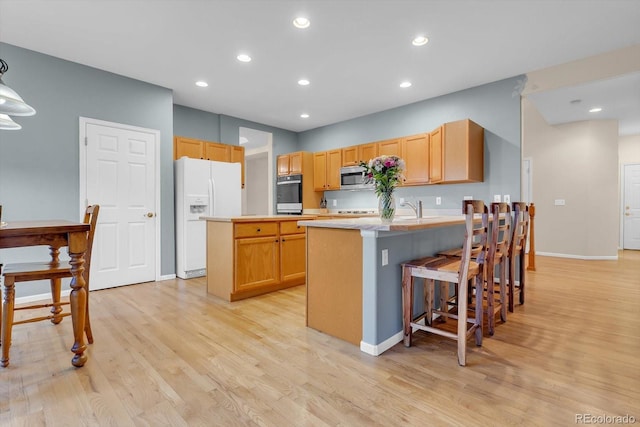 kitchen with stainless steel appliances, light wood-type flooring, a sink, and a peninsula