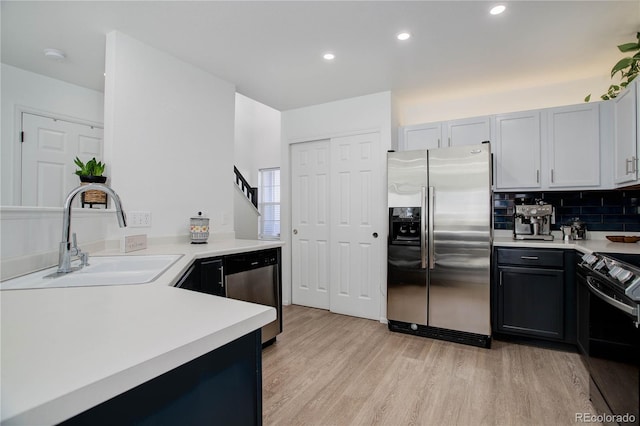 kitchen featuring sink, tasteful backsplash, white cabinetry, light hardwood / wood-style flooring, and stainless steel appliances