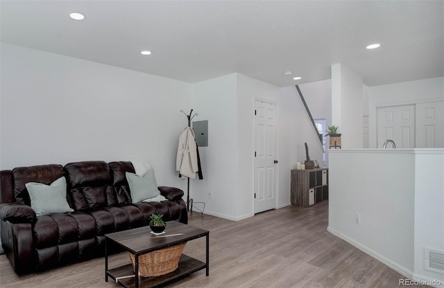 living room featuring electric panel and light hardwood / wood-style floors