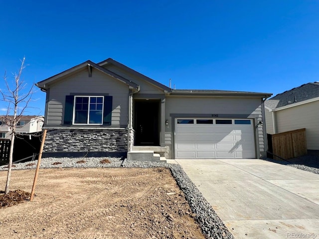 view of front of home with a garage, stone siding, driveway, and fence