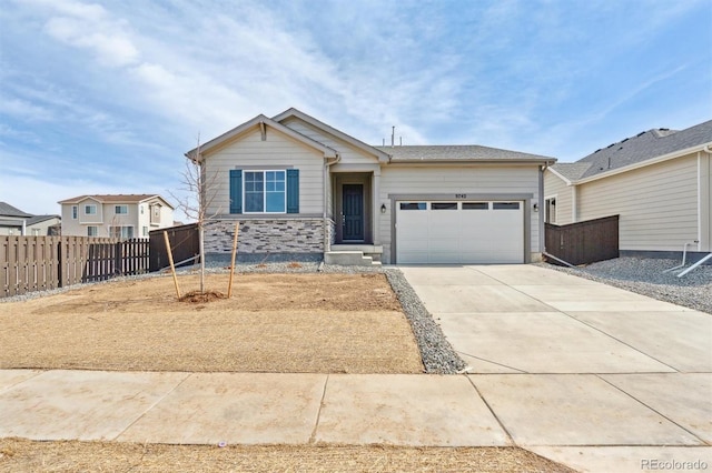 view of front of house featuring stone siding, driveway, a garage, and fence