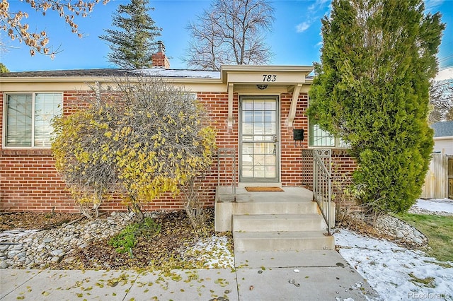 view of exterior entry featuring brick siding and a chimney