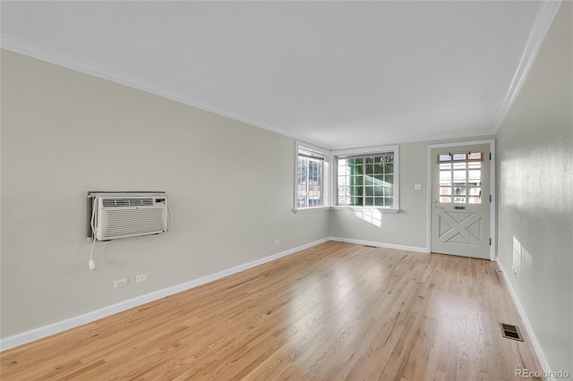 spare room with light hardwood / wood-style flooring, ornamental molding, and a wall unit AC