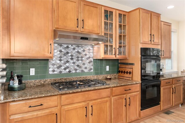 4814 S Upham Ct, Littleton, CO 80123 - kitchen with under cabinet range hood, stainless steel gas stovetop, stone countertops, backsplash, and glass insert cabinets