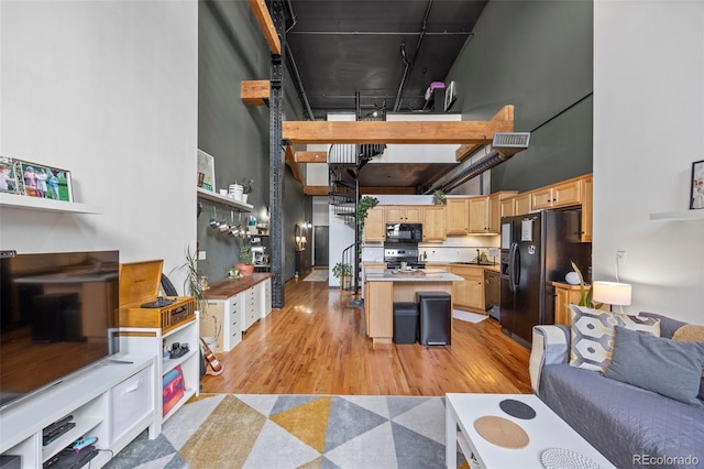 living room with light wood-type flooring and a towering ceiling