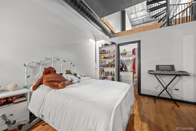 bedroom with wood finished floors and a towering ceiling