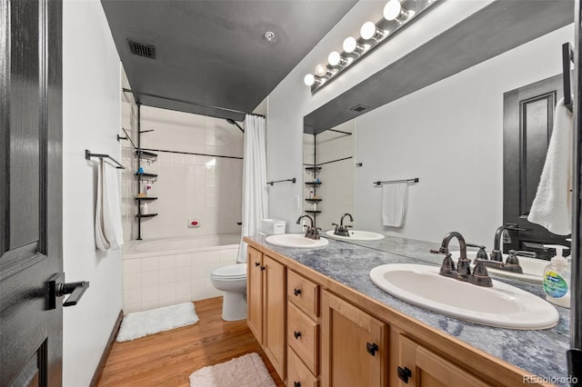 bathroom featuring visible vents, a sink, wood finished floors, and tiled shower / bath combo