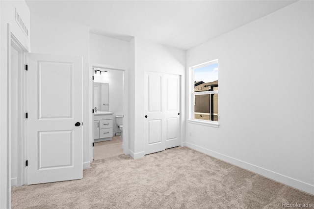 unfurnished bedroom featuring light carpet and ensuite bathroom