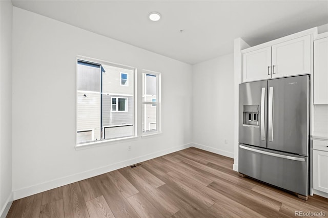 kitchen with white cabinetry, stainless steel fridge, and light hardwood / wood-style flooring