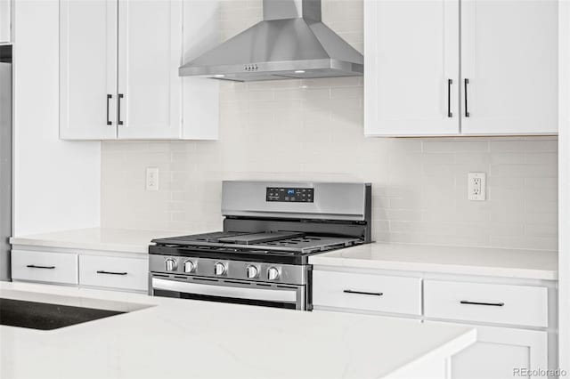 kitchen featuring ventilation hood, gas stove, light stone countertops, and white cabinets