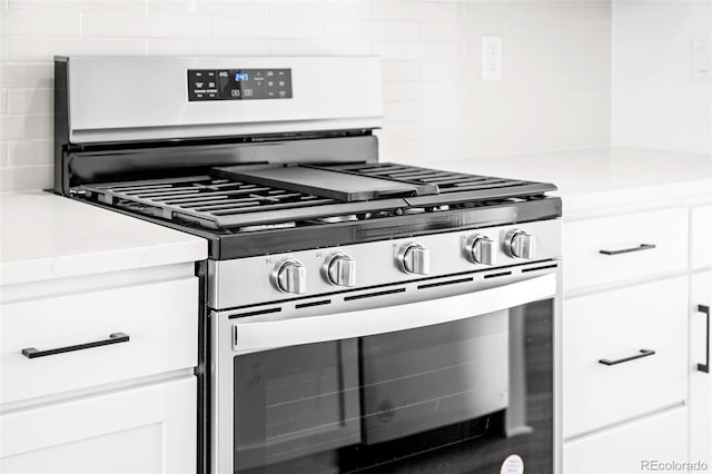 kitchen with white cabinetry, gas stove, and tasteful backsplash