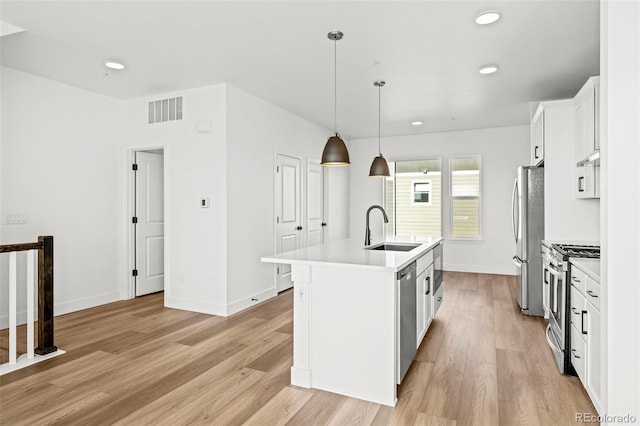 kitchen with white cabinetry, appliances with stainless steel finishes, a kitchen island with sink, and sink