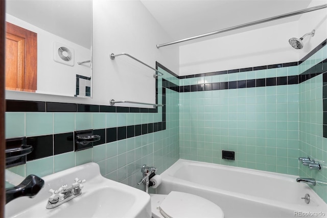 bathroom featuring tile walls, shower / bath combination, visible vents, toilet, and a sink