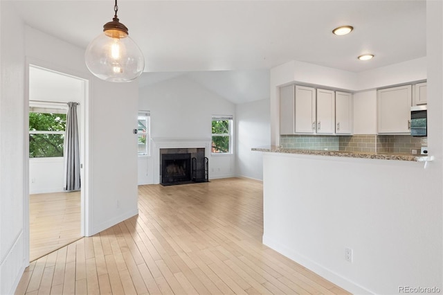 11 W Ellsworth Ave Unit 22, Denver, CO 80223 - kitchen with stainless steel microwave, tasteful backsplash, baseboards, and vaulted ceiling