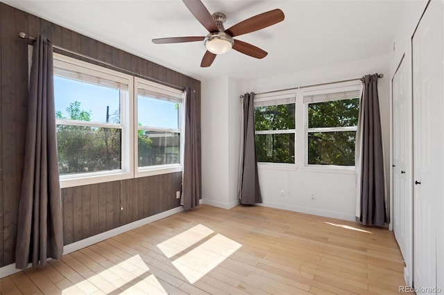 11 W Ellsworth Ave Unit 22, Denver, CO 80223 - unfurnished room with baseboards, light wood finished floors, ceiling fan, and wooden walls