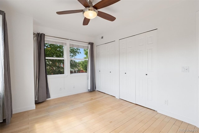 11 W Ellsworth Ave Unit 22, Denver, CO 80223 - unfurnished bedroom with baseboards, two closets, light wood-style flooring, and a ceiling fan