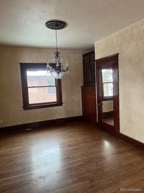 unfurnished dining area featuring an inviting chandelier and dark hardwood / wood-style flooring