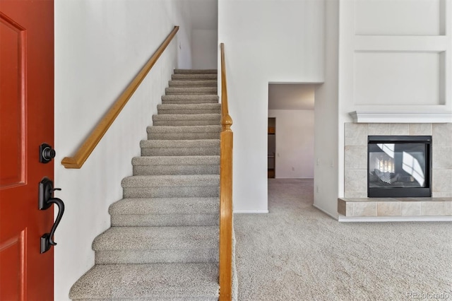 stairs with a fireplace and carpet