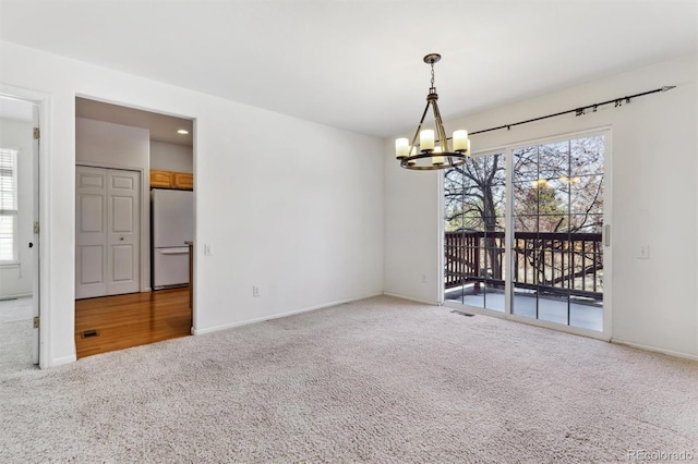 unfurnished room featuring a healthy amount of sunlight, carpet flooring, and an inviting chandelier