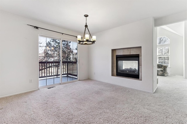 unfurnished living room featuring a notable chandelier, a tile fireplace, and carpet flooring