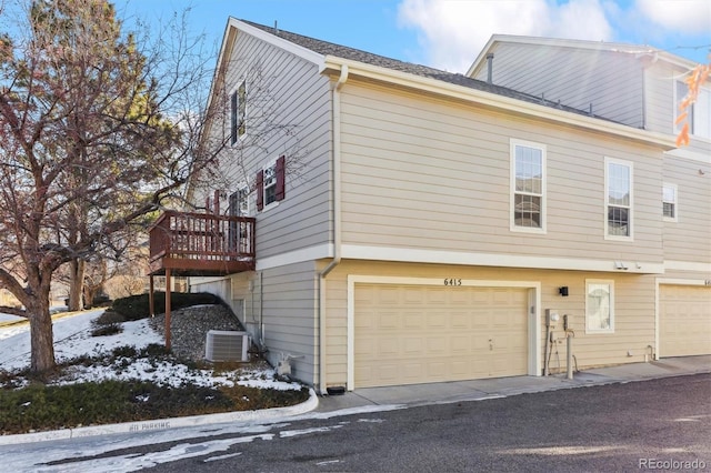 view of snow covered exterior with a garage, cooling unit, and a deck