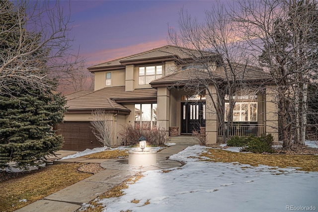 prairie-style home with a garage, a tiled roof, and stucco siding