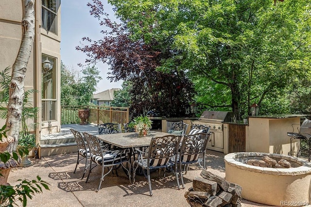 view of patio / terrace with fence, a fire pit, outdoor dining area, and area for grilling