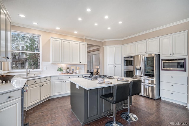 kitchen featuring a center island, a breakfast bar area, stainless steel appliances, white cabinetry, and a sink