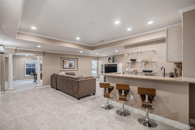 living area with light carpet, a raised ceiling, decorative columns, and recessed lighting