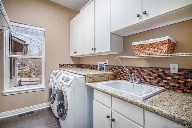 clothes washing area with cabinet space, baseboards, visible vents, washer and dryer, and a sink