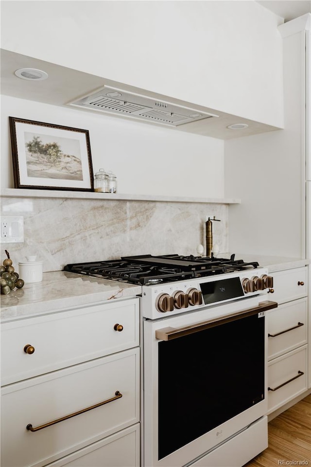 kitchen featuring white cabinetry, light stone counters, light wood-type flooring, white range with gas cooktop, and decorative backsplash