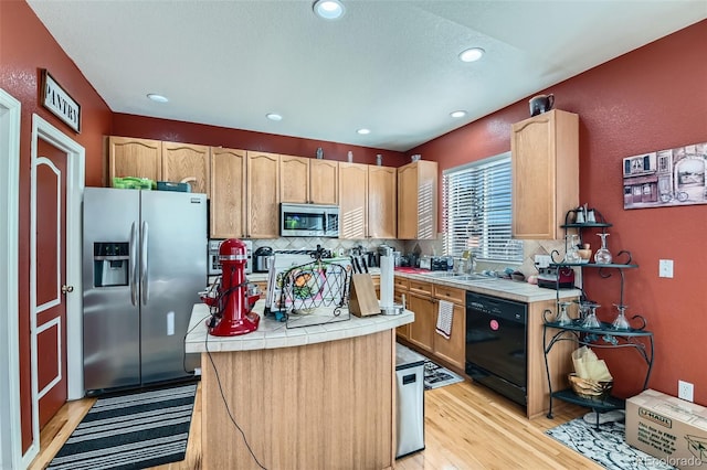 kitchen with tile countertops, decorative backsplash, sink, light hardwood / wood-style flooring, and appliances with stainless steel finishes