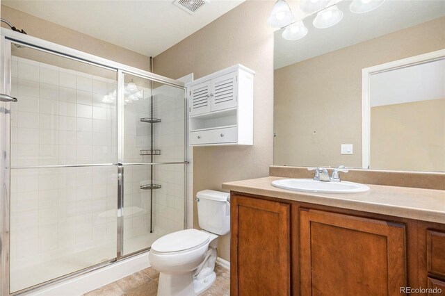 bathroom featuring tile patterned floors, a shower with door, vanity, and toilet