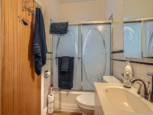 full bathroom featuring hardwood / wood-style floors, vanity, toilet, enclosed tub / shower combo, and tasteful backsplash