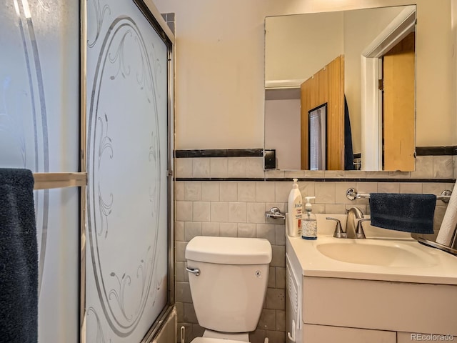 bathroom with vanity, toilet, and tile walls