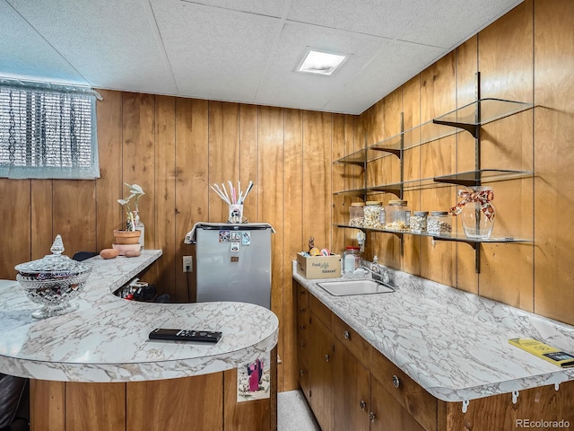 bar featuring stainless steel refrigerator, light colored carpet, sink, and wooden walls