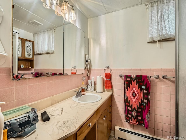 bathroom featuring vanity, baseboard heating, and tile walls