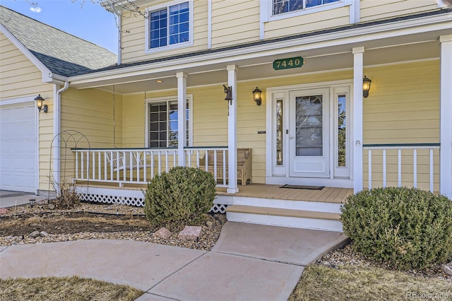 doorway to property with covered porch, an attached garage, and a shingled roof