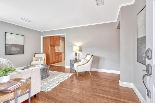 living area with light hardwood / wood-style flooring and ornamental molding