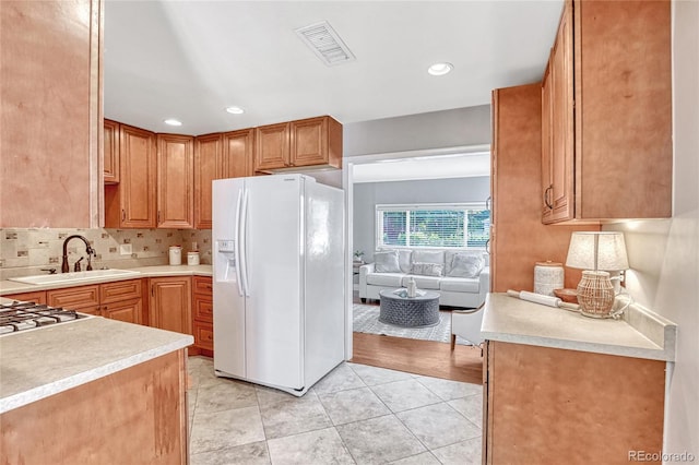 kitchen featuring white refrigerator with ice dispenser, light tile patterned floors, tasteful backsplash, and sink