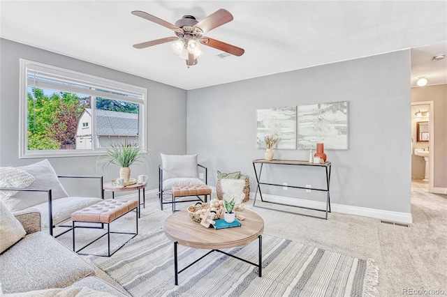 living area with light carpet and ceiling fan