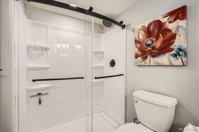 full bath featuring a textured wall, a shower stall, and toilet