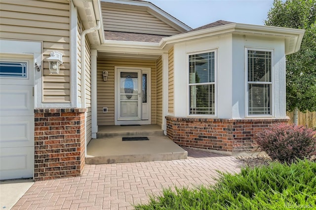 view of exterior entry featuring brick siding and an attached garage